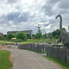 Ein riesiger Dinosaurier wacht über den Himmelsgarten mit Spielplatz.