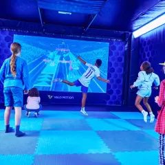 Kinder spielen in Berlin ein interaktives Spiel vor einer großen Leinwand.