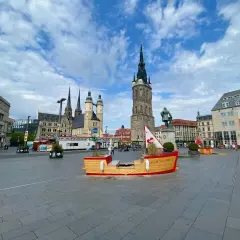 Marktplatz in Halle mit historischer Architektur und einer Boots-Installation. Hier kann man viel entdecken und erleben!