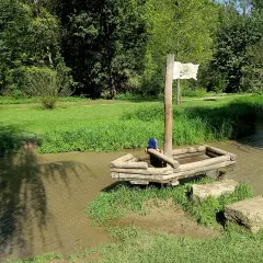 Ein hölzernes Piratenschiff mit einem Kind an Bord im Wolfstal Lauterach. Ein weiteres Kind spielt im Wasser.