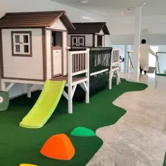 Einladendes **Cafe mit Spielplatz**: Zwei Spielhäuser mit Rutschen, Klettergerüst, Spielzeug und Sitzgelegenheiten für Kinder.