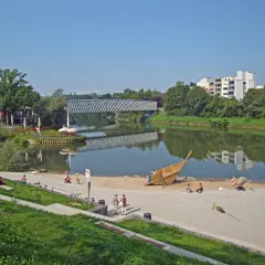 Sonniger Tag am Neckarstrand Remseck mit Menschen am Sandstrand, einem Spielschiff und einer Brücke über dem Fluss.