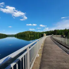 Ein idyllischer Weg führt über eine Staumauer am See. Perfekt für Ausflugsziele Oberbergischer Kreis mit Kindern, um die Natur zu genießen.
