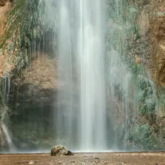 Der Drackensteiner Wasserfall stürzt über moosbewachsene Felsen. Ein einzelner Stein liegt im flachen Wasser am Fuß des Wasserfalls.
