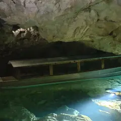 Ein Boot wartet auf Besucher in der Höhle der Zwiefalter Aach. Das klare, grüne Wasser schimmert im Licht.