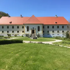 Schloss Ehrenfels bei Hayingen, ein imposantes Gebäude mit rotem Ziegeldach, umgeben von grünen Rasenflächen und Bäumen.