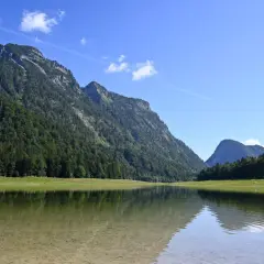 Spiegelglatte See mit Bergkulisse und Wald. Perfekt für eine Wanderung auf dem weitsee rundweg.