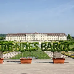 Blühendes Barock im Ludwigsburg Park: Ein prächtiges Schloss mit kunstvoll geschnittenen Hecken, die das Wort "Barock" formen.