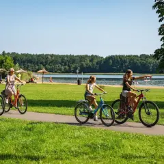 Familie genießt einen sonnigen Urlaub in Brandenburg mit Kindern, radelt am See entlang.