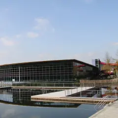 Moderner Badesee Schorndorf mit Glasfassade, Wasserrutschen und Stegen im Wasser.