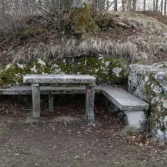 Ein Steintisch und Bänke laden zum Verweilen ein, nahe der ruine Herwartstein. Moosbewachsene Felsen und kahle Äste umgeben die Stelle.