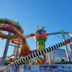Bunte Miramar Rutschen schlängeln sich vor blauem Himmel. Ein fantasievolles Gebilde mit bunten Röhren und einem lustigen Kopf.