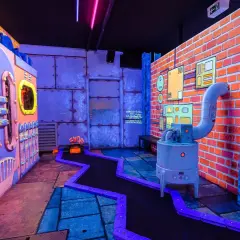Bunte Minigolfanlage in Hamburg abends mit Kindern. Ein verrückter Parcours mit leuchtenden Farben und industriellem Design.