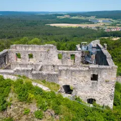 Die **Ruine Bramberg** thront auf einem bewaldeten Hügel. Steinmauern mit leeren Fensterhöhlen und eine Wendeltreppe zeugen von vergangener Pracht.