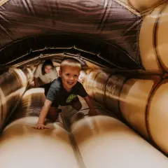 Ein Junge krabbelt lachend durch einen aufblasbaren Tunnel. Ein toller Spaß für **Bayreuth mit Kindern**!