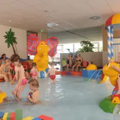 Fröhliche schwimmbad kinder planschen im Wasser, spielen mit bunten Figuren und rutschen. Ein Elefant und eine Schildkröte sorgen für Spaß.