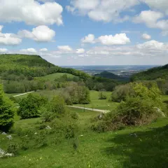 Grüne Hügel und Wiesen, ideal für eine Randecker Maar Wanderung. Wolken ziehen über das weite Tal.