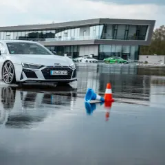 Ein weißer Audi R8 fährt auf nasser Strecke. Hier kann man in Ingolstadt das Fahren auf Eis und Schnee trainieren.