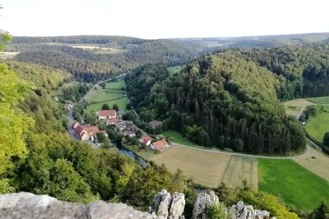 Idyllisches Lautertal Alb mit kleinen Dörfern, Flüssen und bewaldeten Hügeln, aufgenommen von einem Felsvorsprung.