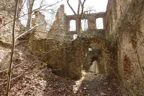 Verfallene Burgruine mit steinernen Mauern und Bögen, die wie ein hoher Turm in den Himmel ragt.