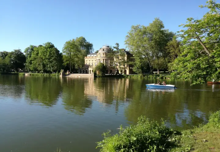 Ein Boot gleitet auf dem Monrepos-See, im Hintergrund das Schloss Monrepos. Der Monrepos-See rundweg lädt zum Spaziergang ein.