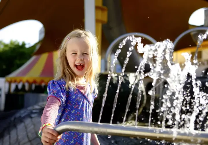 Ein fröhliches Mädchen spielt am Wasserspielplatz im Europa-Park.