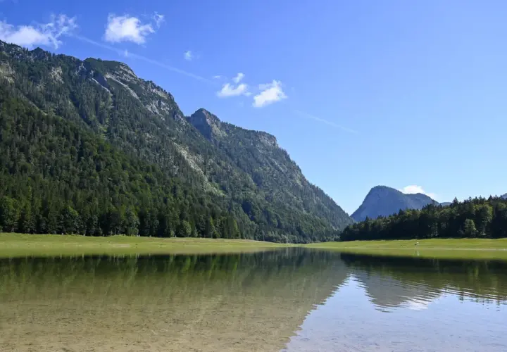 Spiegelglatte See mit Bergkulisse und Wald. Perfekt für eine Wanderung auf dem weitsee rundweg.