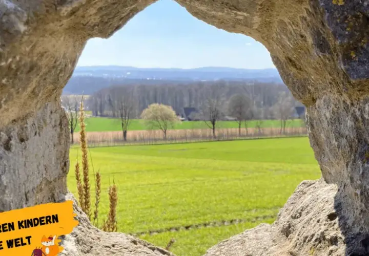 Blick durch eine Felsöffnung auf grüne Felder und Bäume. Ein tolles Motiv für Ausflugsziele Niederrhein, um Kindern die Welt zu zeigen.