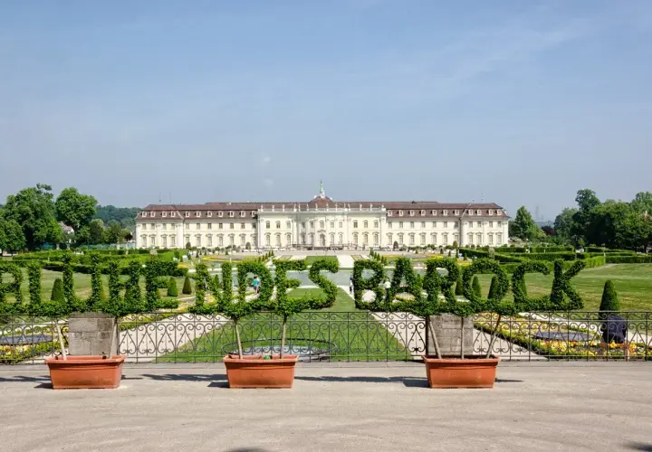 Blühendes Barock im Ludwigsburg Park: Ein prächtiges Schloss mit kunstvoll geschnittenen Hecken, die das Wort "Barock" formen.