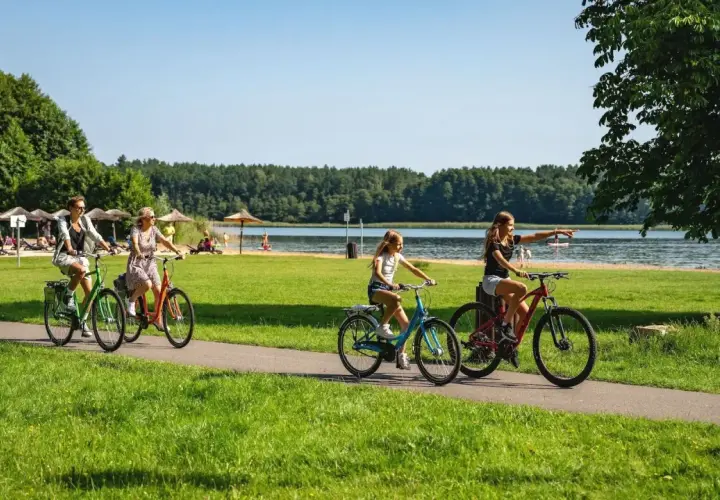 Familie genießt einen sonnigen Urlaub in Brandenburg mit Kindern, radelt am See entlang.