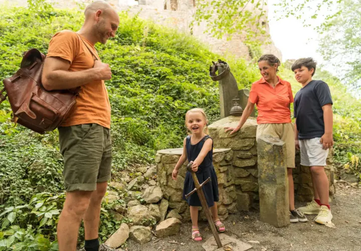 Familie erkundet die Eifel mit Kindern. Ein kleines Mädchen zieht stolz ein Schwert aus einem Stein.