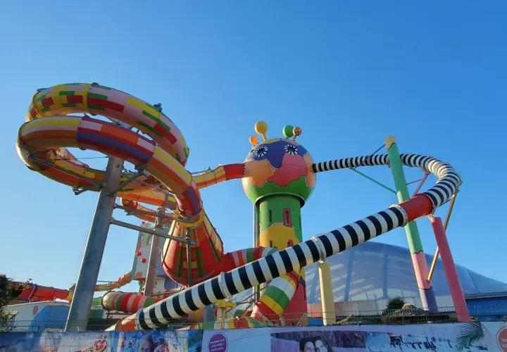 Bunte Miramar Rutschen schlängeln sich vor blauem Himmel. Ein fantasievolles Gebilde mit bunten Röhren und einem lustigen Kopf.