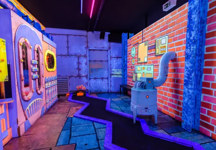 Bunte Minigolfanlage in Hamburg abends mit Kindern. Ein verrückter Parcours mit leuchtenden Farben und industriellem Design.