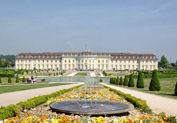 Prachtvolles Barockschloss Ludwigsburg mit symmetrischen Gärten und einem blühenden Blumenbeet vor einem Brunnen.