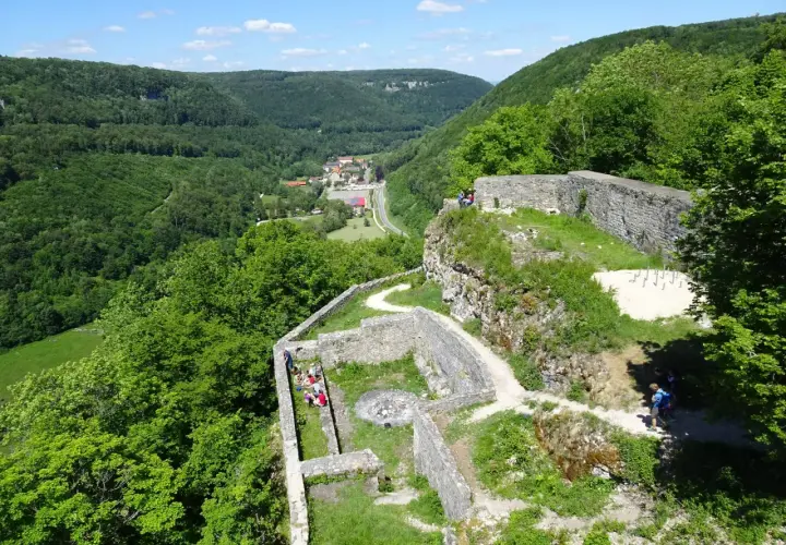 Ruinen der Burg Hohenwittlingen, umgeben von grünen Wäldern, mit einem Dorf im Tal.