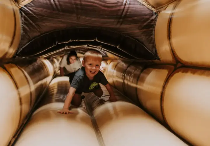Ein Junge krabbelt lachend durch einen aufblasbaren Tunnel. Ein toller Spaß für **Bayreuth mit Kindern**!
