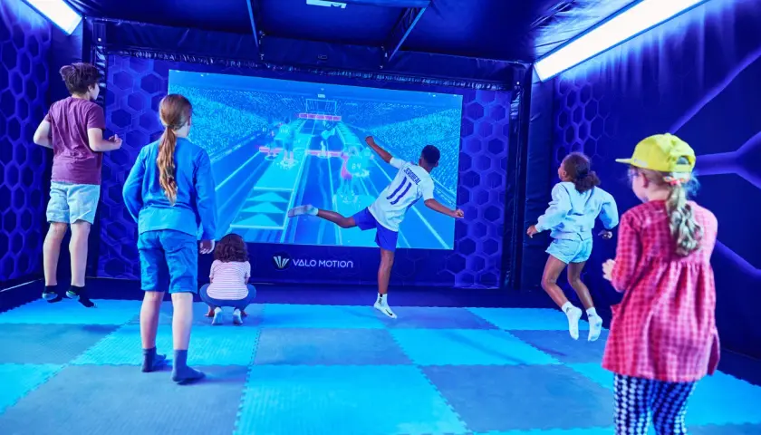 Kinder spielen in Berlin ein interaktives Spiel vor einer großen Leinwand.