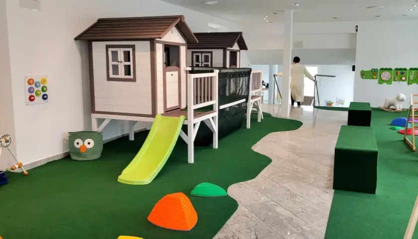 Einladendes **Cafe mit Spielplatz**: Zwei Spielhäuser mit Rutschen, Klettergerüst, Spielzeug und Sitzgelegenheiten für Kinder.