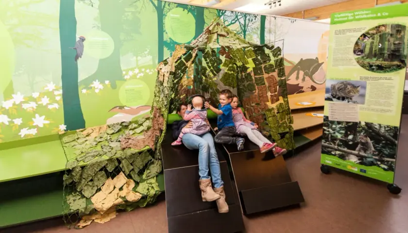 Familie erkundet im Naturparkzentrum Zaberfeld eine Wald-Ausstellung mit interaktiver Hütte.