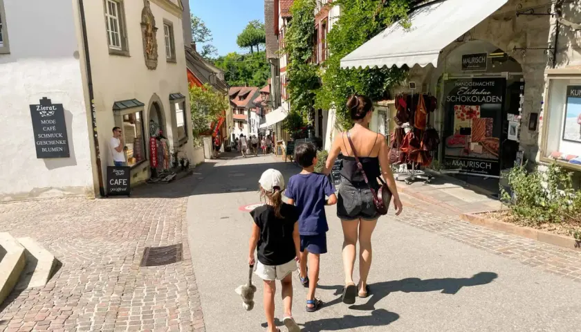 Familie spaziert durch eine Gasse am Bodensee mit Kindern, vorbei an Geschäften und Cafés.