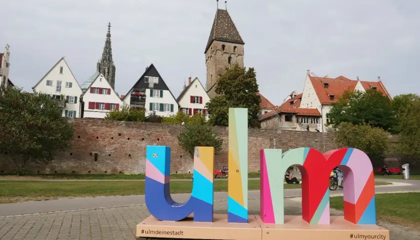 Bunte Buchstaben mit "#ulmdeinstadt" und "#ulmyourcity" vor historischer Kulisse. Hier kann man Ulm erleben!