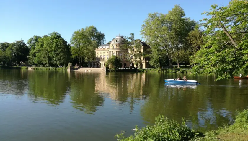 Ein Boot gleitet auf dem Monrepos-See, im Hintergrund das Schloss Monrepos. Der Monrepos-See rundweg lädt zum Spaziergang ein.