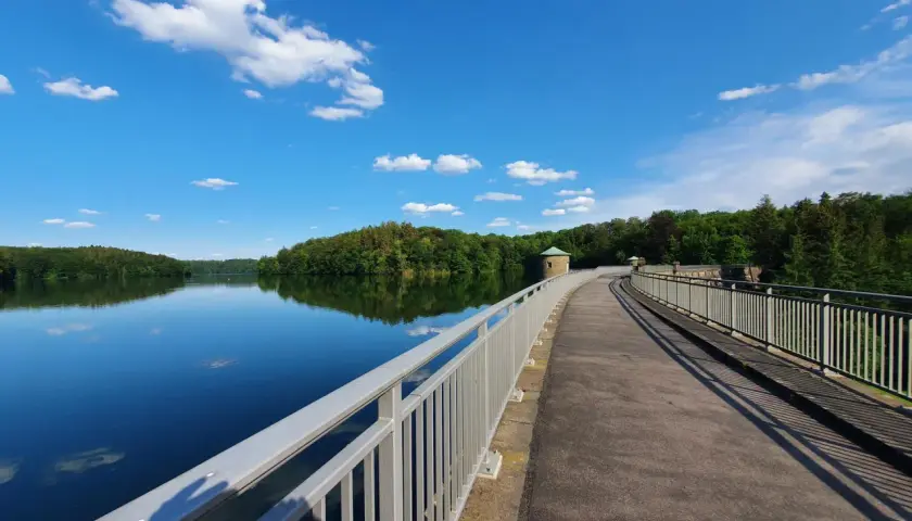 Ein idyllischer Weg führt über eine Staumauer am See. Perfekt für Ausflugsziele Oberbergischer Kreis mit Kindern, um die Natur zu genießen.