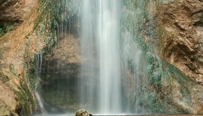 Der Drackensteiner Wasserfall stürzt über moosbewachsene Felsen. Ein einzelner Stein liegt im flachen Wasser am Fuß des Wasserfalls.