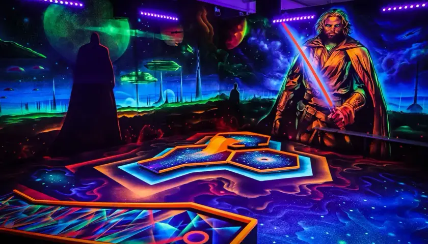 Galaktisches indoor schwarzlicht minigolf mit leuchtenden Bahnen und Weltraum-Kulisse. Ein Jedi mit rotem Lichtschwert wacht über das Spiel.