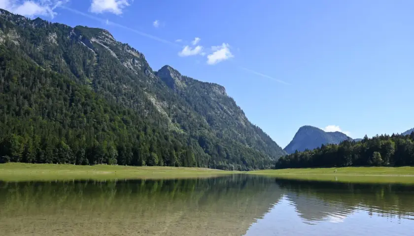 Spiegelglatte See mit Bergkulisse und Wald. Perfekt für eine Wanderung auf dem weitsee rundweg.