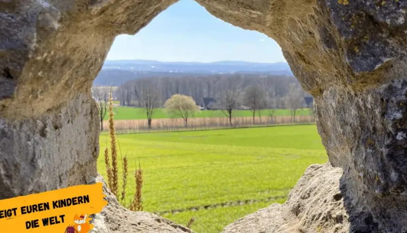 Blick durch eine Felsöffnung auf grüne Felder und Bäume. Ein tolles Motiv für Ausflugsziele Niederrhein, um Kindern die Welt zu zeigen.