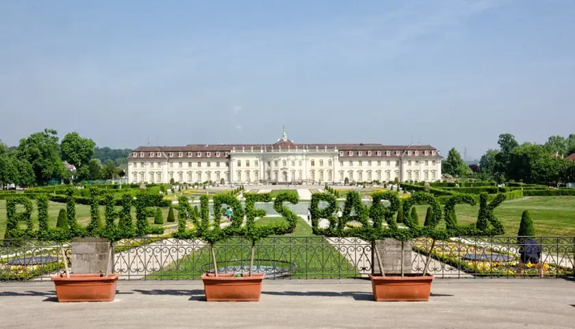 Blühendes Barock im Ludwigsburg Park: Ein prächtiges Schloss mit kunstvoll geschnittenen Hecken, die das Wort "Barock" formen.