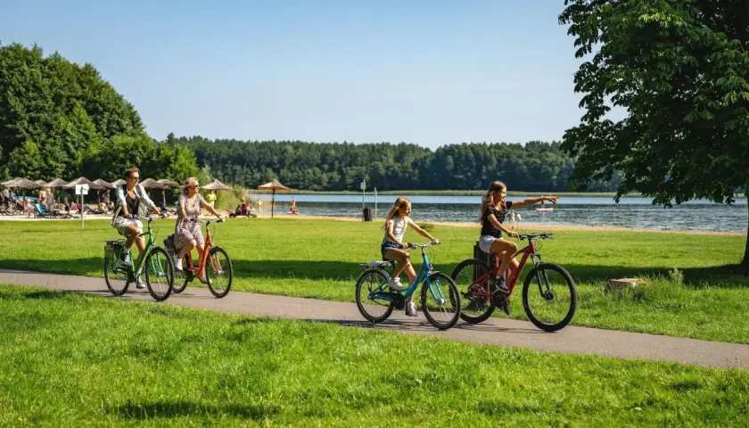 Familie genießt einen sonnigen Urlaub in Brandenburg mit Kindern, radelt am See entlang.