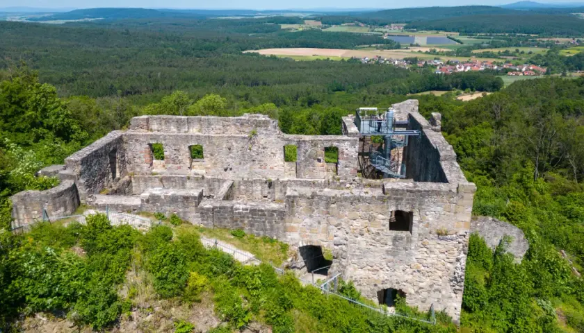 Die **Ruine Bramberg** thront auf einem bewaldeten Hügel. Steinmauern mit leeren Fensterhöhlen und eine Wendeltreppe zeugen von vergangener Pracht.